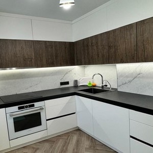 Современная светлая кухня с деревом.  Фасады кухни выполнены из МДФ в цвете Агератум белый матовый и Лесной орех; ручки Gola; стеновая панель Slotex Кварцит; еврозапил.