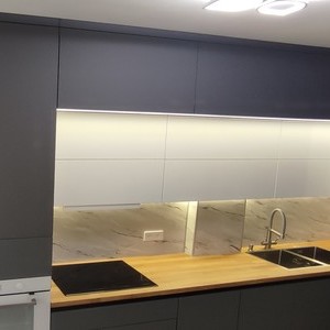 Угловая кухня с антресольными шкафами и ручкой Gola. Фасады МДФ серые матовые и белый глянец. Встроенная морозильная камера, посудомоечная машина. Подъемные механизмы BLUM AVENTOS HK-S. Подсветка интегрированна в дно антресольных шкафов и в дно верхнего яруса кухни.Фартук Аргус светлый Скиф.